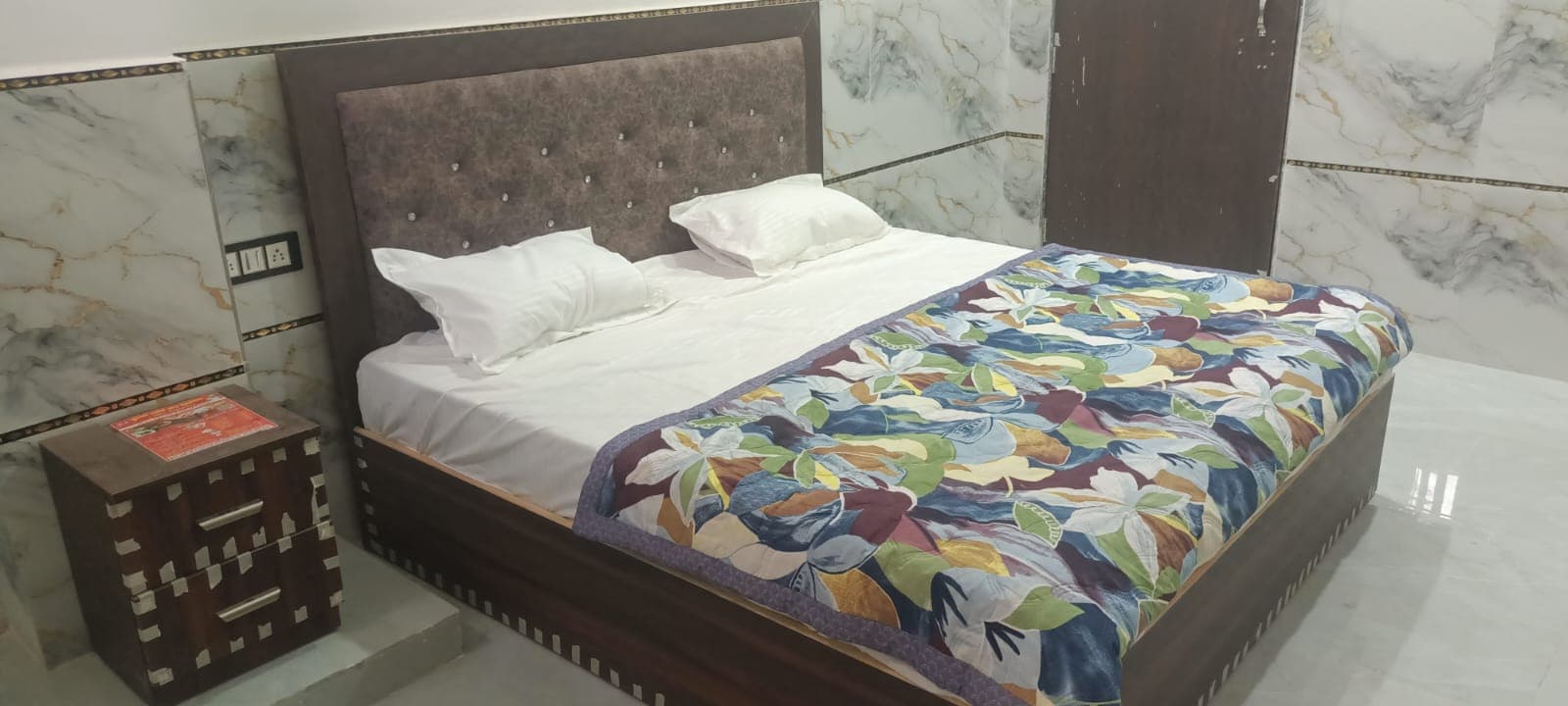 Double bed with upholstered headboard, white linen and a bedside table